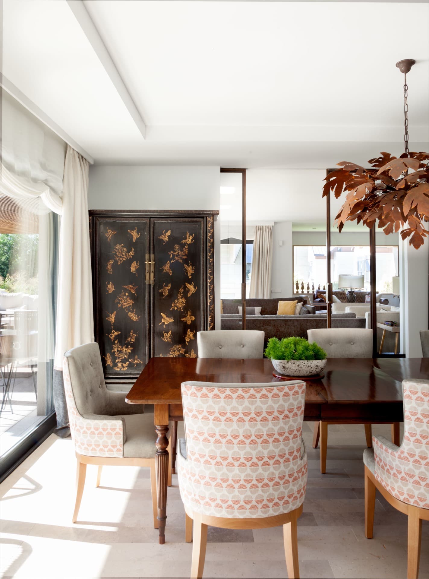 Comedor con mesa de madera, sillas tapizadas y biombo oriental