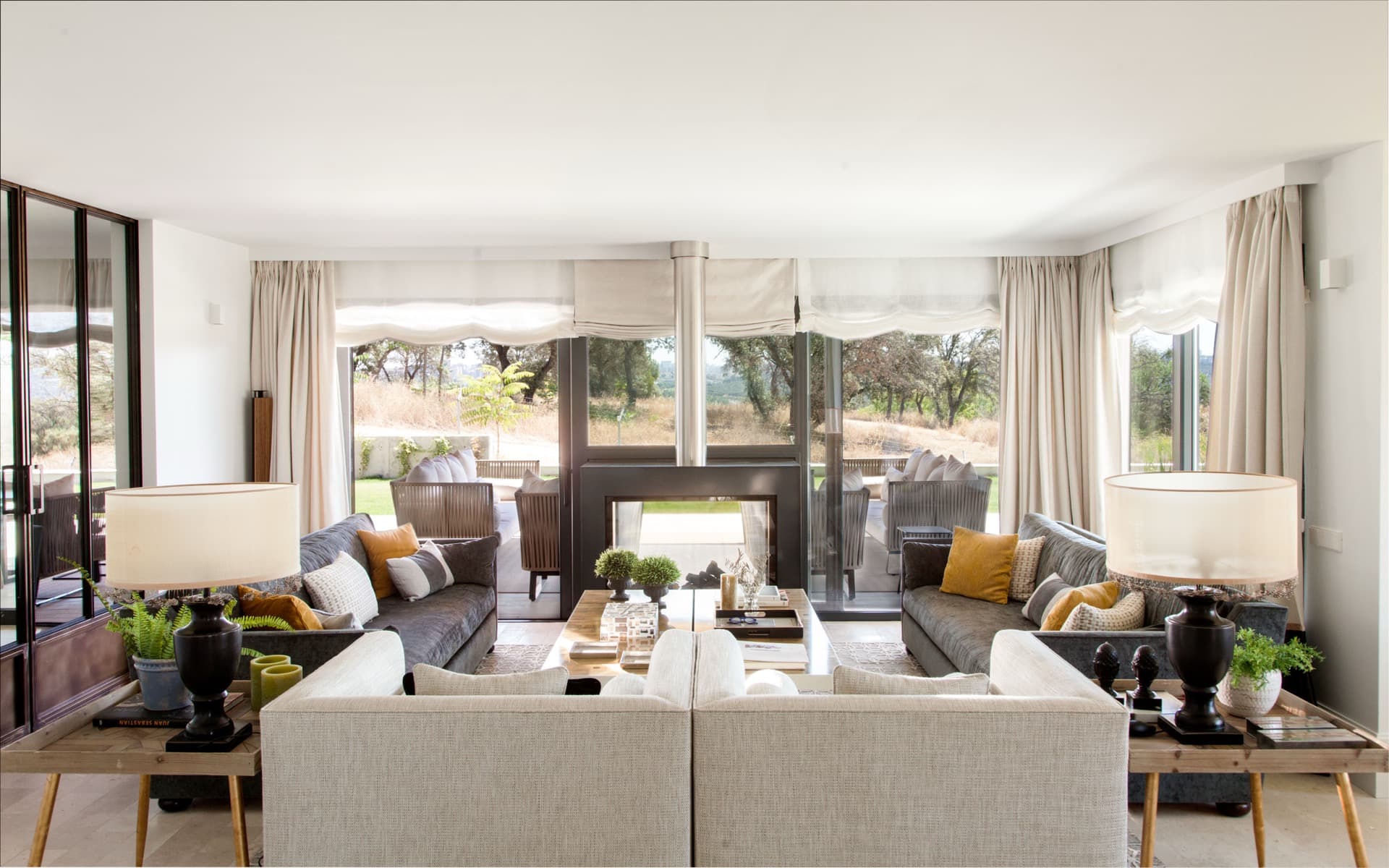 Salón luminoso con sofás tapizados, chimenea y vistas al jardín