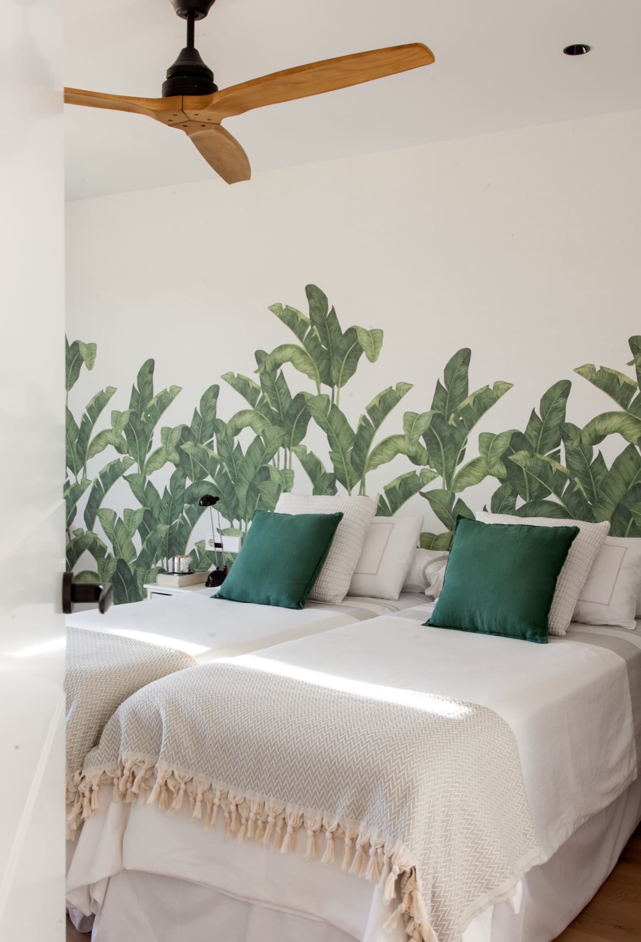 Dormitorio sereno con mural vegetal y ropa de cama en tonos naturales